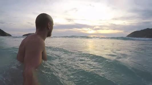 A man gracefully swims in the ocean at sunset, embodying the serenity and beauty of Ageless Societies